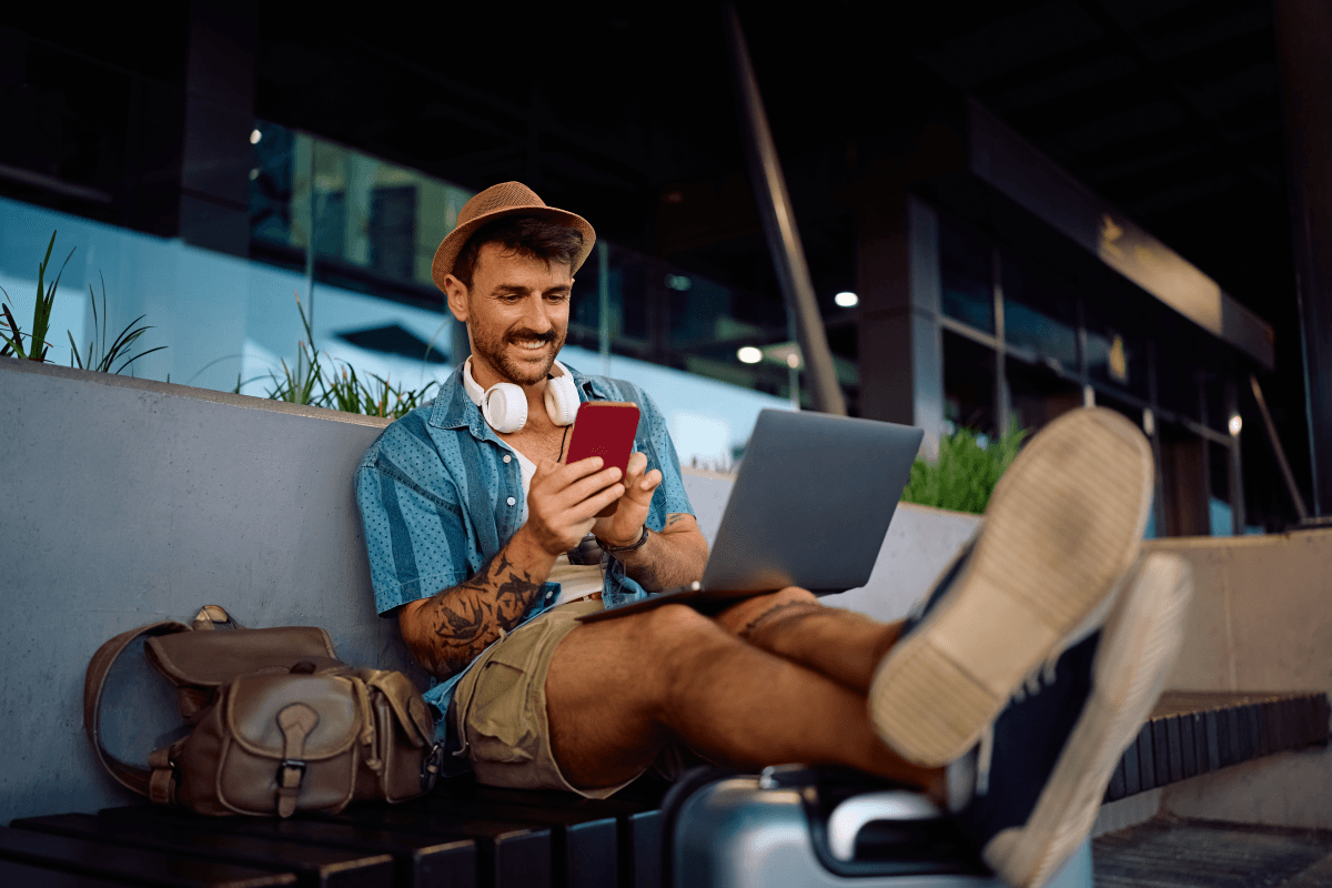 Happy traveler using laptop and phone